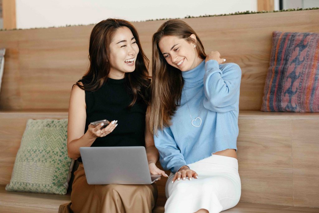 To personalise your marketing plan, engage your audience. These two women in the image, for example. They laugh and smile while looking at something on a laptop screen